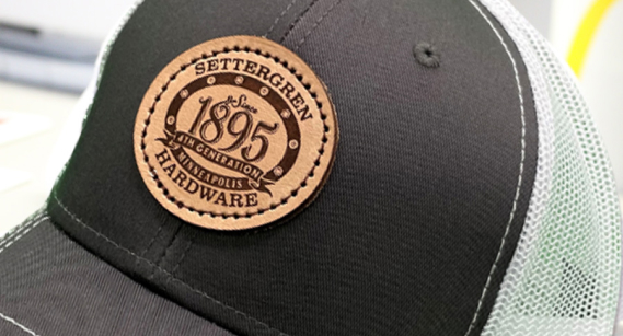 Genuine leather patch with custom laser etched design on black mesh hat